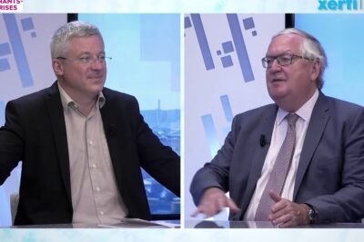 Two suited professionals in a split-screen studio discussion about systeme financier 1.