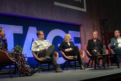Panel of speakers on stage discussing taloudellinen jarjestelma during a conference