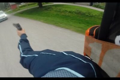 First-person view of tapoja pitaa extending an arm holding a handgun along a residential street