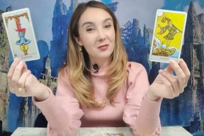 Woman holding two tarot cards during a reading including tarotens lyckohjul 1.