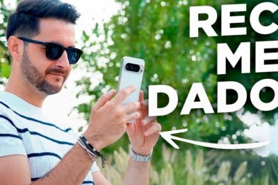 Man wearing sunglasses and a striped shirt holding a white smartphone outdoors labeled telefonos moviles 1.