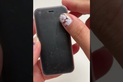 Small pink telephone portable with a smudged black screen held in a hand