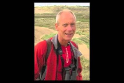 Person in red jacket with binoculars on sandy dunes, terapeutisk kloning visual