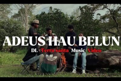 Several people seated around a small campfire in a wooded clearing, music video still from terra santa 1.