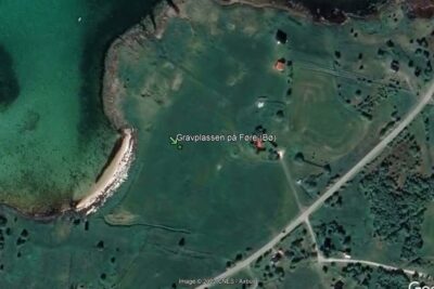 Aerial satellite view of a turquoise bay, sandy shore and surrounding green farmland suggesting tidligere tider.