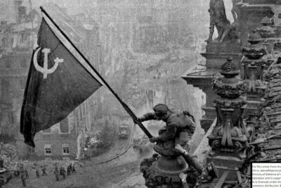 Soldiers hoisting a hammer and sickle flag atop a ruined rooftop during toisen maailmansodan 1