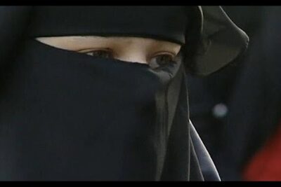 Close-up of a person's eyes visible through a black niqab, tragen burka.