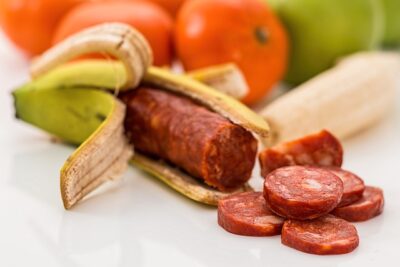 A peeled banana containing a chorizo-style sausage with sliced rounds beside it, visually prompting transgeeniset ruoat puolesta vai vastaan discussion.