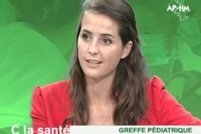 Woman TV presenter in a red jacket speaking on a show about transplantation dorganes and pediatric grafts.