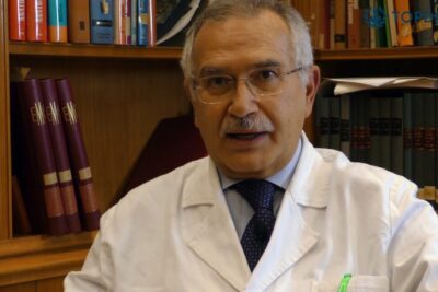 Senior physician in a white coat speaking about trapianto organi in a medical office