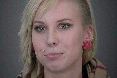 Close-up portrait of a young blonde woman with rose-shaped earrings and a facial piercing for tupakoinnin lopettaminen 2.