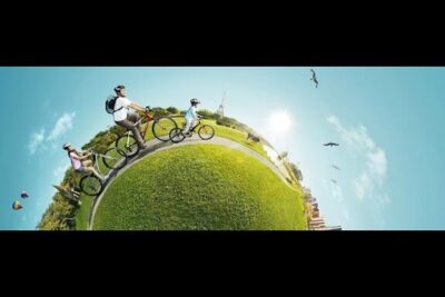 Family cycling on a curved grassy path showcasing turismo sostenibile and low-impact outdoor recreation.