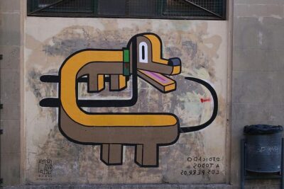Colorful stylized dog graffiti on a weathered wall with bold black outlines and a nearby trash bin — tutkimukset ovat.