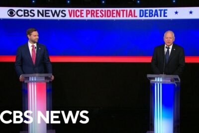 Televised CBS News vice presidential debate stage with two podiums and CBS logo suitable for twitter ar