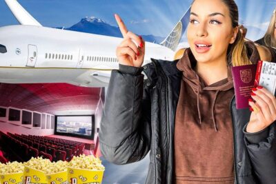 Smiling traveler holding passport and boarding pass in front of an airplane and cinema with popcorn for ulkomaille toiden