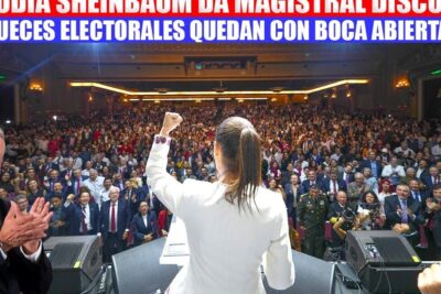 Speaker on stage raising a fist to a cheering packed auditorium during an urfolks rettssystem event