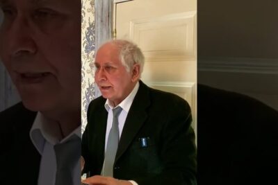 Elderly man in suit and tie speaking indoors about uskonto myos
