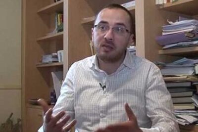 Man in glasses and striped shirt gesturing in an office interview about uso burca.