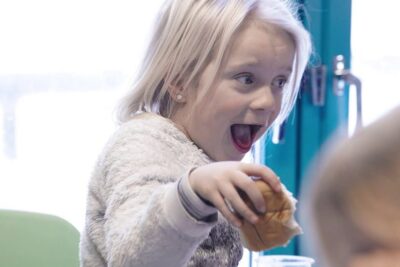 Excited young child reaching for a pastry, a candid moment highlighting usunn mat in a snack setting.