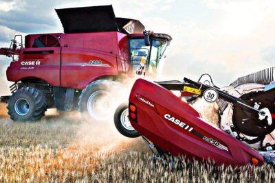 Red Case IH combine harvester with front header cutting wheat in a dusty field, vaikka krakenin.