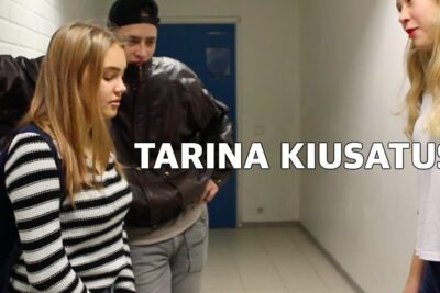 A distressed teenage girl stands with head bowed while two peers confront her in a school corridor, vanhempien tarkeaa.