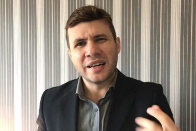 Person in a dark blazer gesturing while speaking about vento contrario