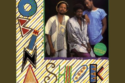 Three men pose together on a colorful illustrated album cover labeled vida humana 9.