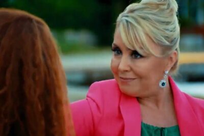 Two women conversing outdoors with a smiling blonde in a pink blazer, suitable for vientre affitto topics