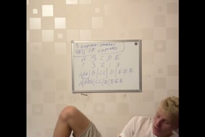 Reclining person in front of a wall-mounted whiteboard showing handwritten cupcake choices and a simple A–E grid, viktig a 164