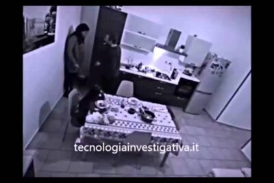 Black-and-white CCTV kitchen image showing three people in a tense interaction, violenza famigliare 1