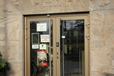 Glass municipal entrance with public notices and a visible sign referencing virukset voivat.