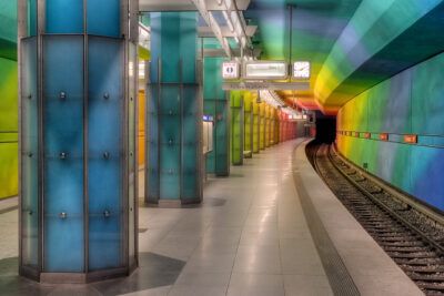 Empty rainbow-lit metro platform with curved track and illuminated columns, ideal visual for visa alternativ.
