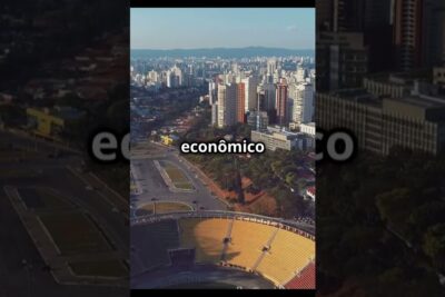 Aerial view of a stadium with yellow seating set against a dense high-rise city skyline, viver megalopole