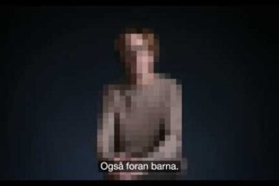 Pixelated portrait of an anonymous person against a dark background with a visible subtitle, vold familien 1.