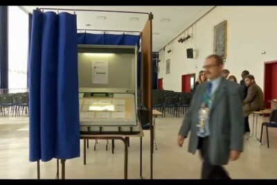 Polling booth with vote electronique touchscreen machine and privacy curtain in a community voting hall.