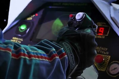 Gloved hand gripping a joystick on a cockpit control panel vuonna 2022.