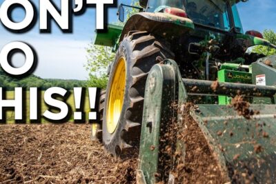 Green tractor tilling soil with debris flying as part of wildlife management 1 habitat preparation.