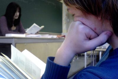 A student attentively reading a textbook during a yhteiskunta 4 social studies class.