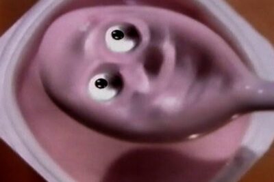 Pink berry yoghurt ar in a cup with a spoon and playful eye-like swirls.