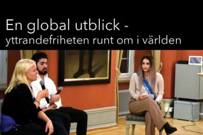 Three panelists seated with microphones discussing yttrandefrihet ar in a small conference room