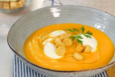 Silky zanahoria legume carrot soup topped with cream, golden croutons and a parsley sprig.